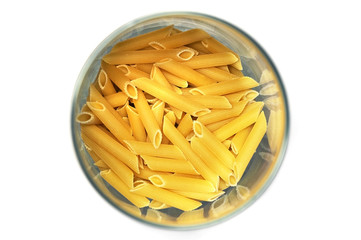 Uncooked pasta in a glass cup top view. Isolated.