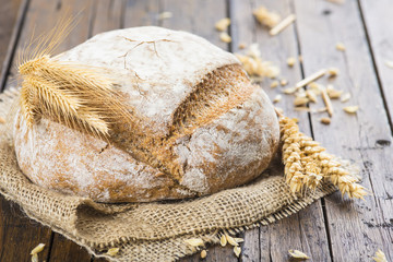 Hogaza de pan de cereales variados sobre arpillera rústica con espigas de trigo y centeno para la comida