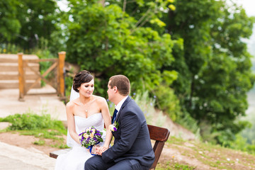 Naklejka premium attractive bride and groom sitting on a bench