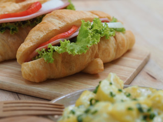 soft focus croissant ham and cheese sandwich on wood plate