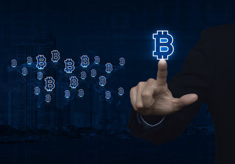 Businessman pressing bitcoin icon with light blue world map conn