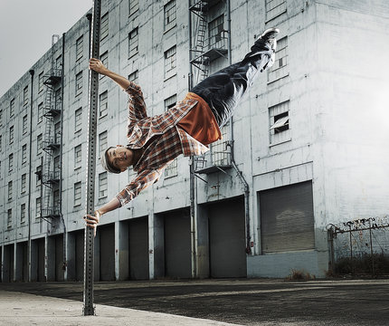 Young man breakdancing, leaping in air, and stretching out