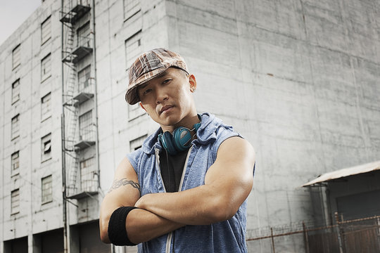 A young person in a denim sleeveless shirt, arms folded looking at the camera, 