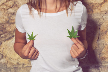 Closeup of young woman holding cannabis leaves in her hands