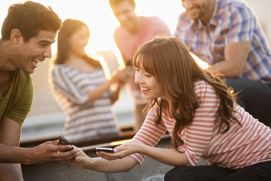 A group of men and women on a rooftop terrace having a party, 