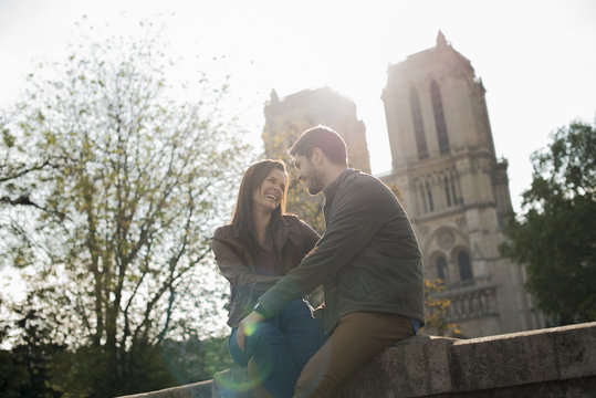 A couple in a romantic  side by side with arms around each other outside Notre Dame Cathedral in Paris,