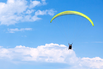 Paragliders in bright blue sky with clouds
