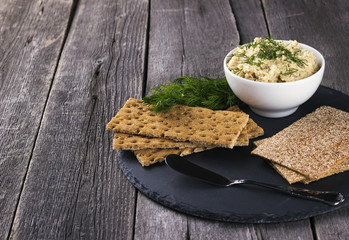 Fish pate with crackers against a dark background