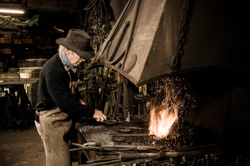 Ironworker forging hot iron in workshop