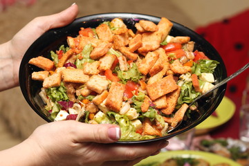 Hands holding an healthy fresh salad with croutons and cheese in bowl