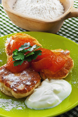 Pancakes with powder, cream and apricot jam on a plate. Wooden bowl with flour