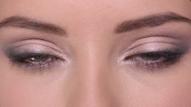 Closeup of opens women's eyes with color eye makeup.