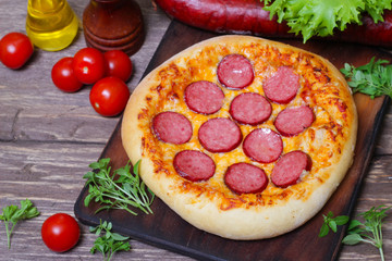 Hot Homemade Pepperoni Pizza on a wooden background with vegetables Ready to Eat