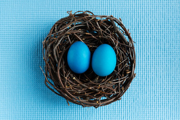 Blue Easter eggs in the nest on blue background