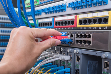 man working in network server room with fiber optic hub for digi