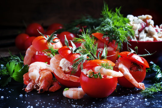 Tomatoes stuffed with shrimp and vegetables on a dark background