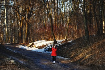 girl in red coat was frozen in the middle of a spring forest. She's trying to warm his hands