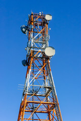 Fototapeta na wymiar Radio/Telecommunication Tower in white and orange with blue sky