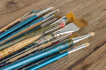 Obraz premium Artist paint brushes over rustic wooden texture