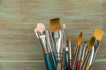 Artist paint brushes over rustic wooden texture.