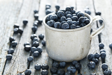 Blueberries in mug on a blue wooden background