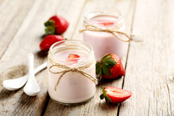 Strawberry yogurt in glass on a grey wooden table