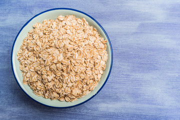 Oat flakes in a bowl on rustic textured background