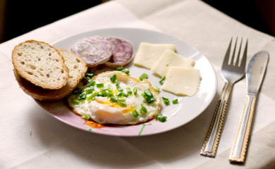light breakfast on the table with egg, bread, cheese and sausage