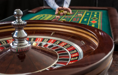 Roulette and piles of gambling chips on a green table. 