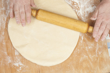 Hands baking dough with rolling pin