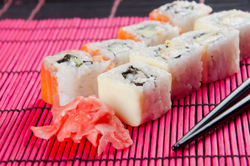 Sushi rolls, ginger and chopsticks (on a bright red bamboo background)