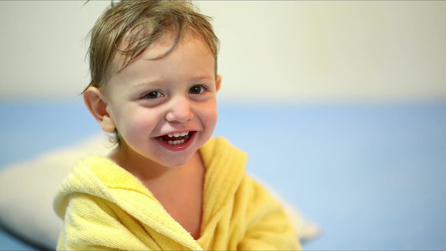 Cute baby wearing a bath robe laughing after bath