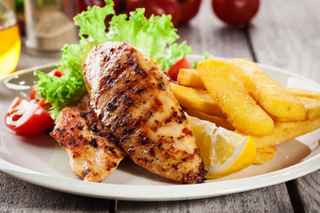 Grilled chicken breasts served with fries and fresh salad