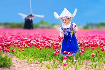 Dutch girl in tulip field in Holland - obrazy, fototapety, plakaty