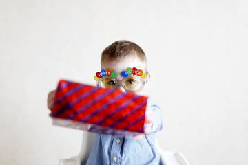 child gives a gift to someone. little boy sitting in a high chair and presents a gift. selective focus. copy space for your text