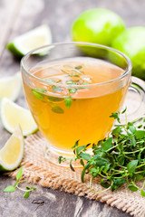 Green  tea with thyme and lime on rustic wooden background