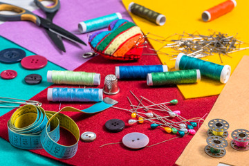 Various sewing accessories on a colored felt. - obrazy, fototapety, plakaty