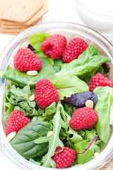 Green  salad with arugula and berries and pine nuts on white