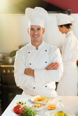 Portrait of a man chef standing in the kitchen arms crossed.