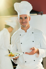 Portrait of a man chef presenting a plate of fine food.
