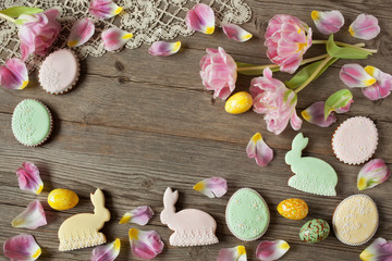 Easter wooden background with eggs, cakes, bunnies and tulips