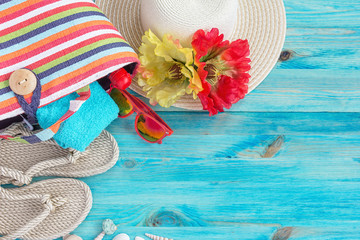 Beach bag, hat and other beach stuff  on blue wooden background.