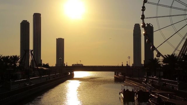Sunset over Al Qasba canal and ferris wheel in Sharjah city, United Arab Emirates. Sharjah - third largest and third most populous city in UAE, after Dubai, and the capital of the emirate of Sharjah