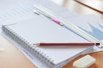 Pencils, notebooks and chart on table in office