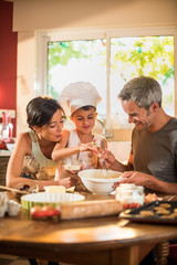Happy 7 years old girl with chef hat is cooking with her parents