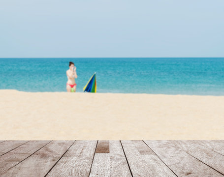 Wood table top on blurred blue sea and white sand