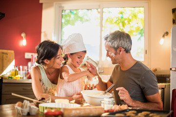 7 years old girl with chef hat is having fun with parents