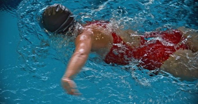 Directly above view of female sportswoman swimming front crawl in the pool