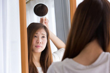 手鏡で頭頂部を見る女性