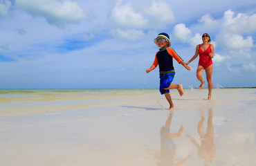 mother and son running in water on beach